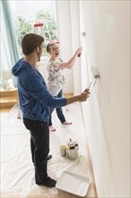 Smiling couple painting wall.