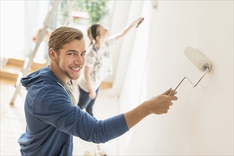 Smiling couple painting wall.