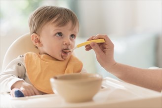 Mother feeding small boy (2-3) with spoon.