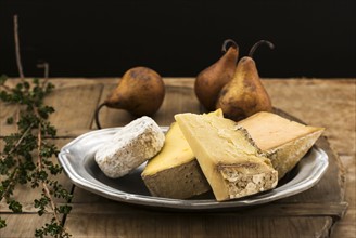 Still life with cheese and pears on wooden table, studio shot.