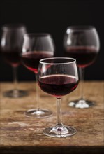 Red wine in glasses on wooden table, studio shot.