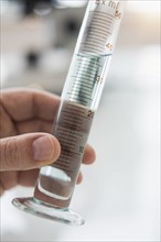 Close up of man's hand holding test tube with liquid.