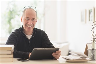 Portrait of smiling mature man working in home office .