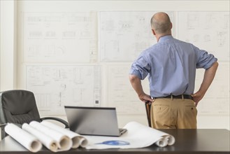 Mature architect looking at blueprints in office.