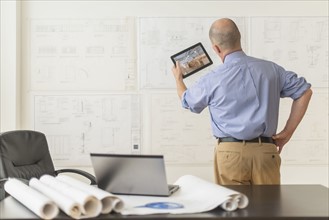 Mature architect using digital tablet in office.