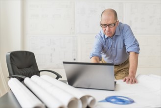 Mature architect using laptop in office.