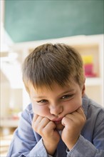 Portrait of frustrated boy (6-7) sitting in classroom