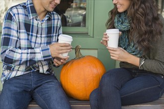 Young couple sitting on bench with coffee cups