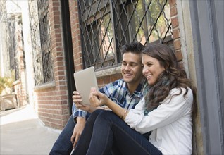 Couple using tablet on sidewalk