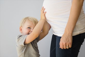 Portrait of boy (2-3) touching his pregnant mom's stomach