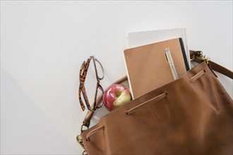 Studio Shot of shoulder bag with apple and notebook in it