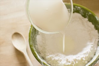 Pouring milk into bowl with flour