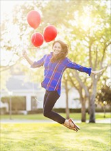 Woman holding balloons jumping