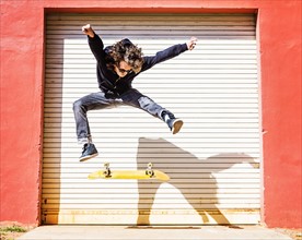 Man jumping on skateboard against closed garage door