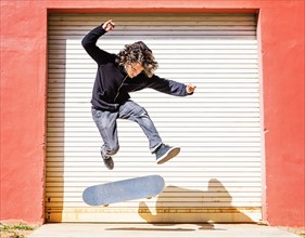 Man jumping on skateboard against closed garage door