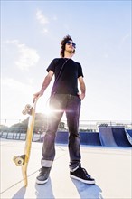 Man leaning on skateboard in skatepark