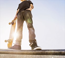 Man leaning on skateboard in skatepark