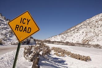 Road sign by snowcapped road in winter