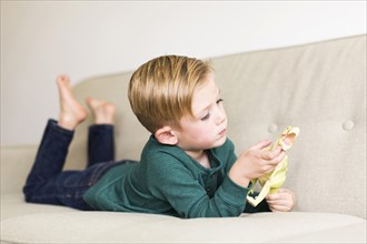 Boy (2-3) playing with toy dinosaur on sofa