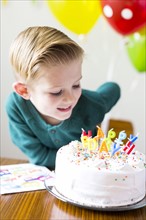 Boy (2-3) looking at birthday cake