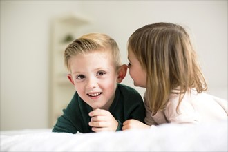 Siblings (2-3, 4-5) whispering in bedroom
