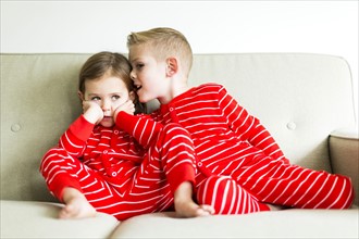 Siblings (2-3, 4-5) in red pajamas whispering