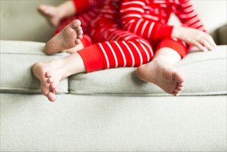 Feet of siblings (2-3, 4-5) in red pajamas