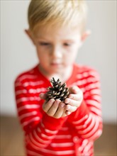 Boy (2-3) holding pine cone