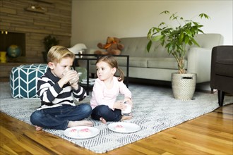 Brother (6-7) and sister (4-5) drinking milk on living room floor