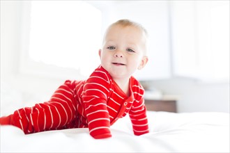 Boy (2-3) in striped pajamas crawling on bed