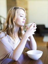 Young woman drinking coffee at table