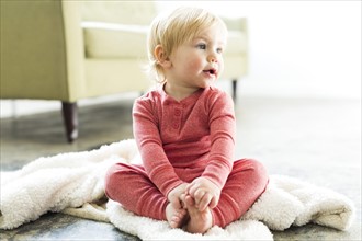 Baby boy (2-3) sitting on blanket in living room