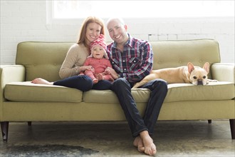 Family with baby son (2-3) and pug on sofa