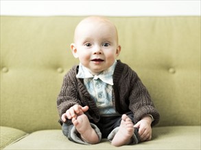 Baby boy (6-11 months) sitting on sofa