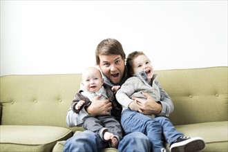 Father embracing two sons (6-11 months and 2-3 years)