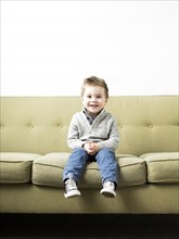 Baby boy (2-3) sitting on sofa