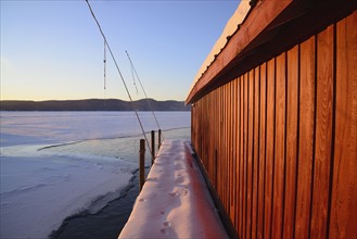 Red Boat House and snow covered pier at edge of lake