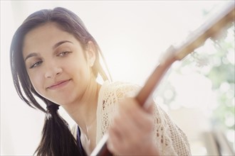 Teenage girl (14-15) playing guitar.