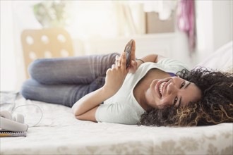 Portrait of teenage girl (16-17) texting in bedroom.