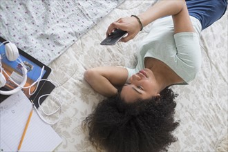 Teenage girl (16-17) texting in bedroom.
