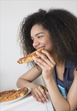 Teenage girl (16-17) eating pizza.