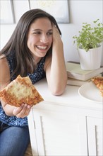 Teenage girl (14-15) eating pizza.