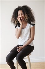 Portrait of teenage girl (16-17) sitting on stool.