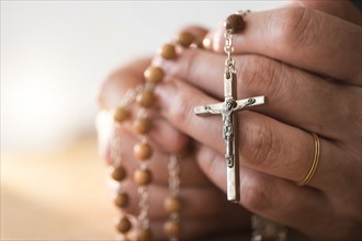 Woman praying with rosary beads in hands.