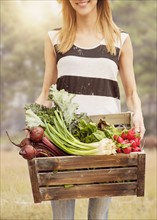 Woman carrying fresh vegetables in box.