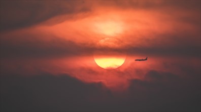 Silhouette of airplane against setting sun.