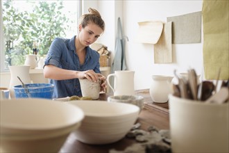 Young woman making pottery in studio.