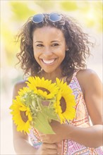 Portrait of smiling woman with sunflowers