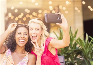 Female friends taking selfie with smart phone in cafe