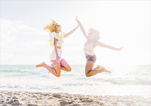 Female friends jumping on beach